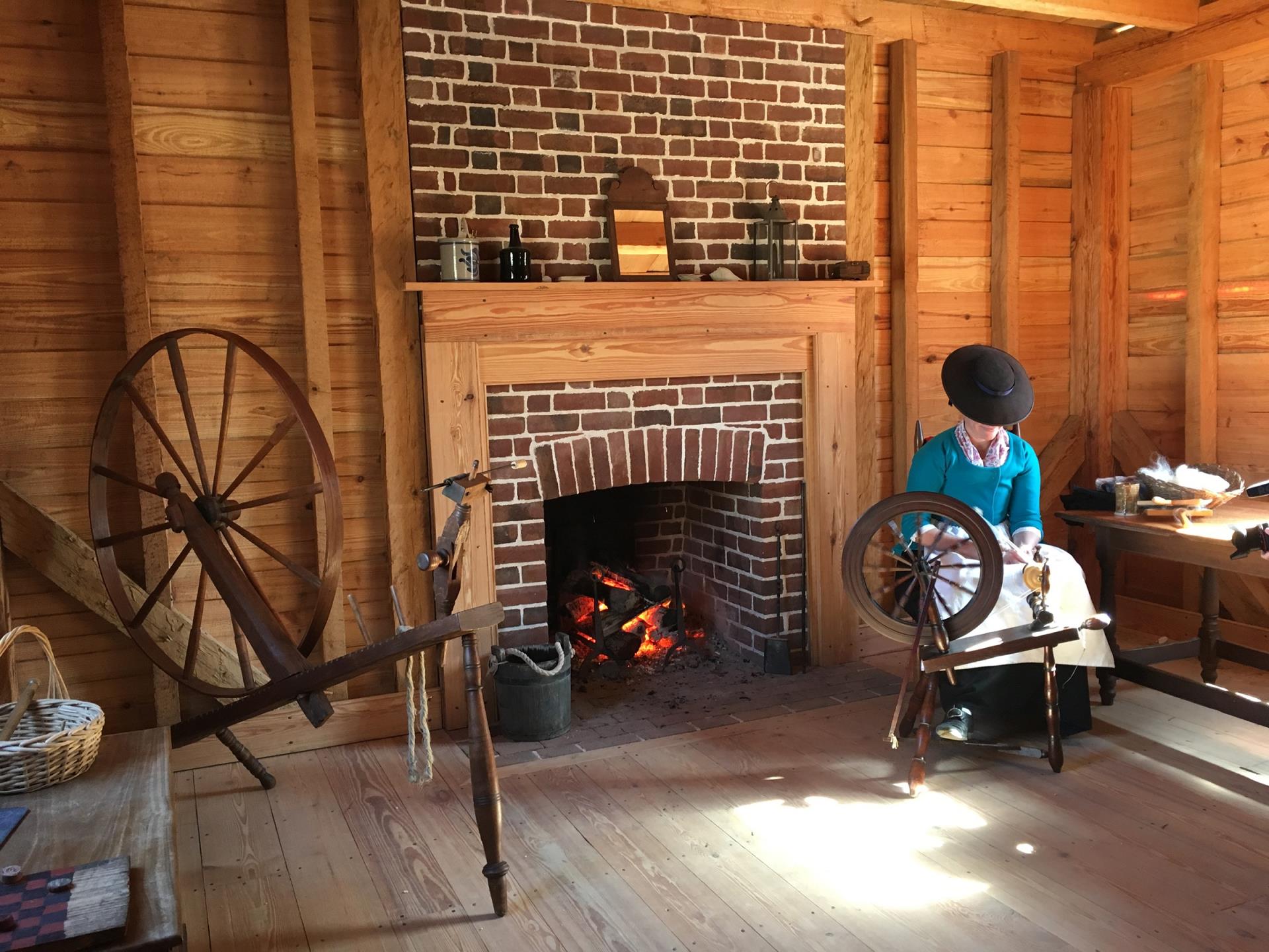 A historical interpreter at the Revolution-era farm spins wool in the farmhouse parlor.