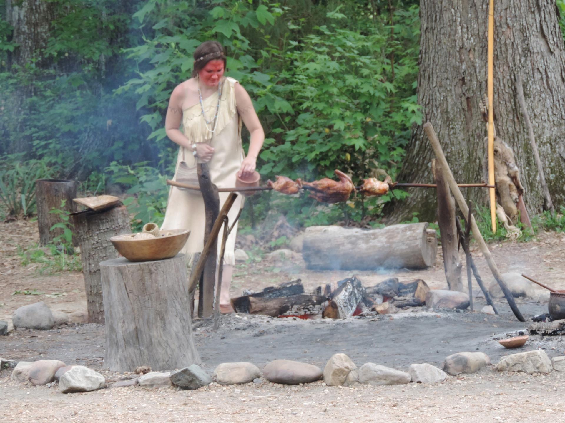 An Indigenous woman cooking on a fire outdoors