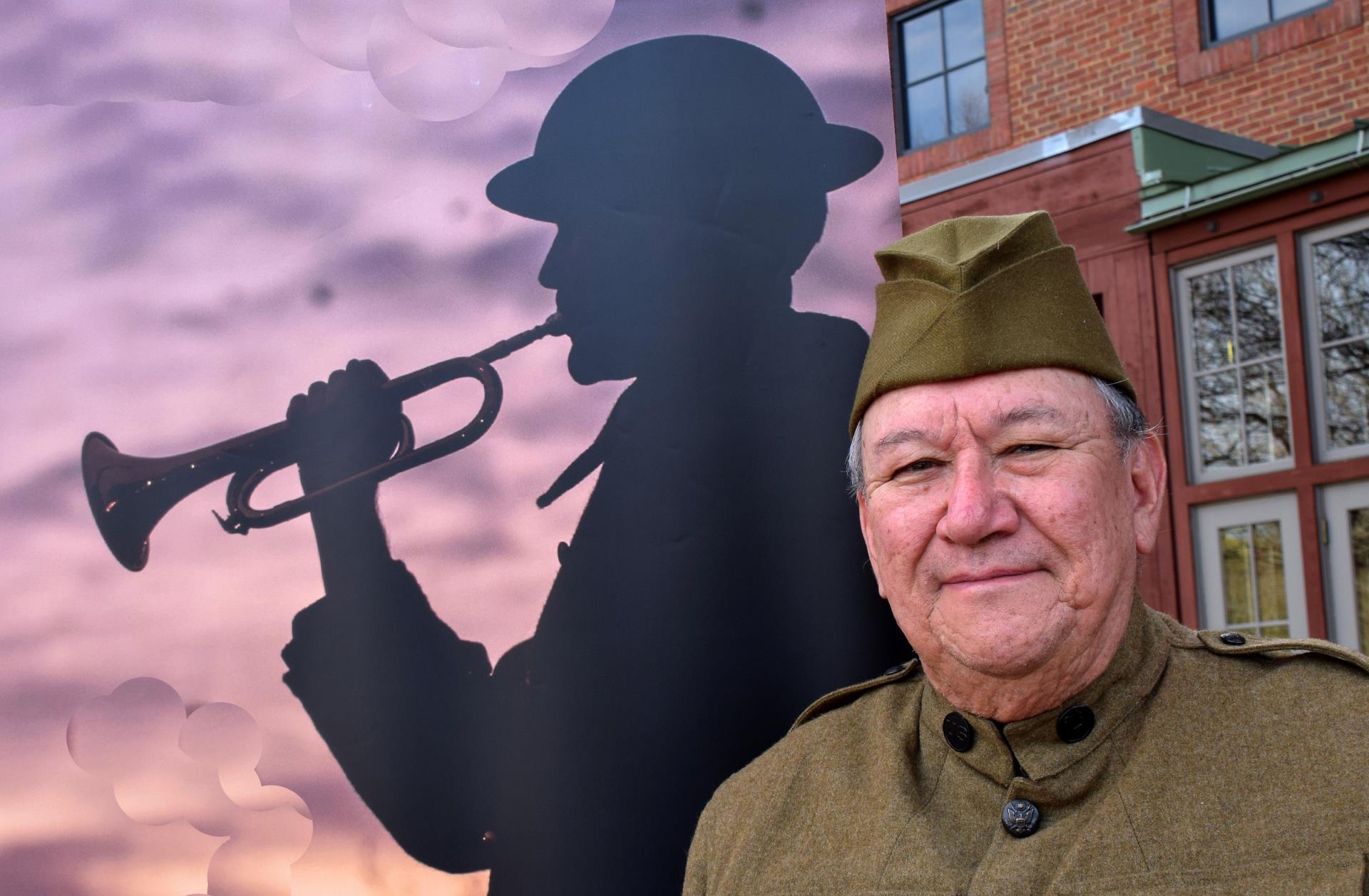 Jari Villanueva stands in front of an image of a Doughboy bugler