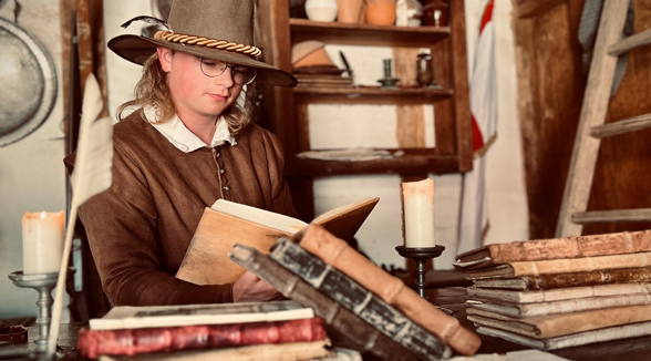 A man in 17th century costume reading a book