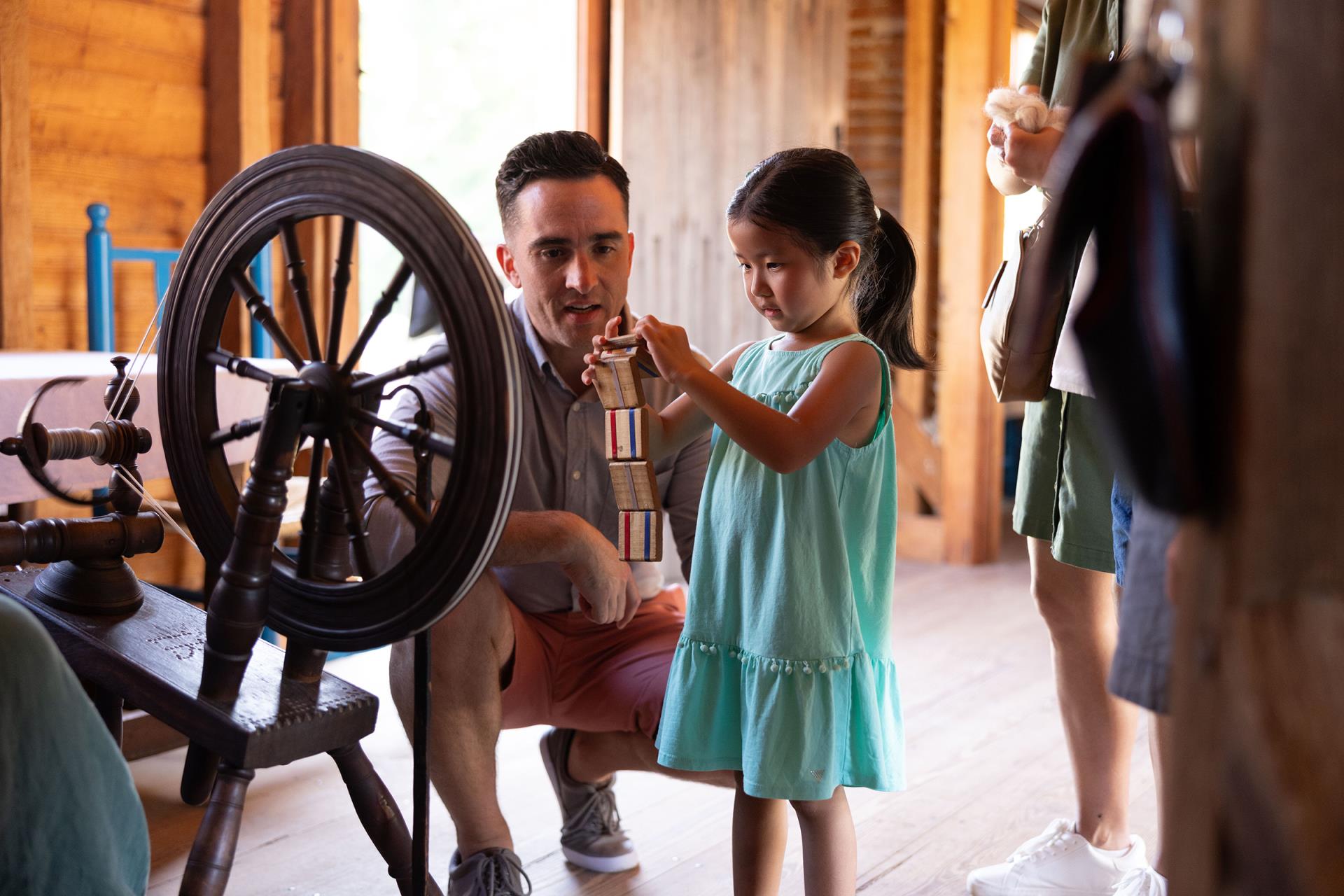 A family explores children's games in the American Revolution Museum at Yorktown farmhouse.