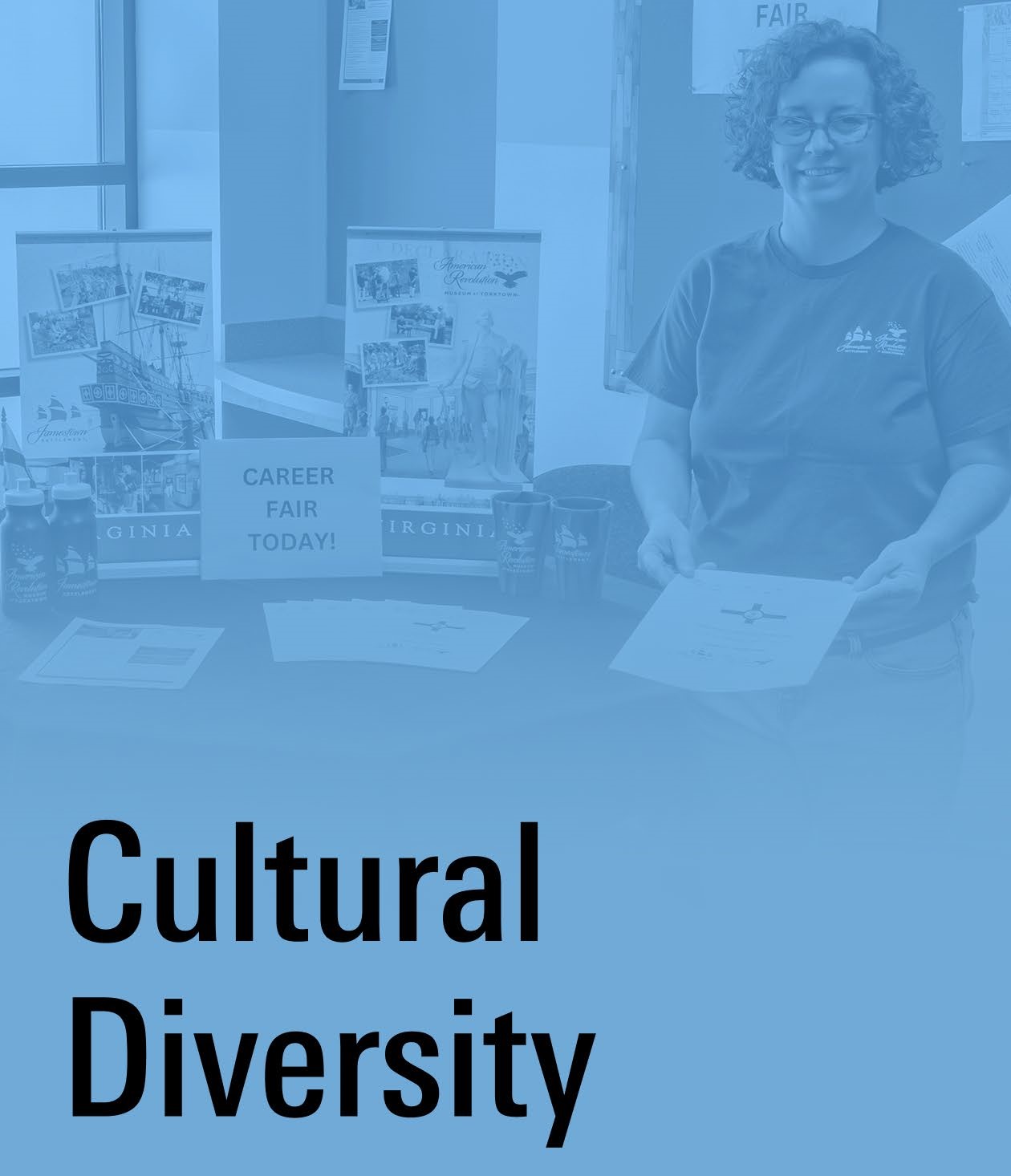 A smiling woman stands near a display table with a blue overlay and text "Cultural Diversity"