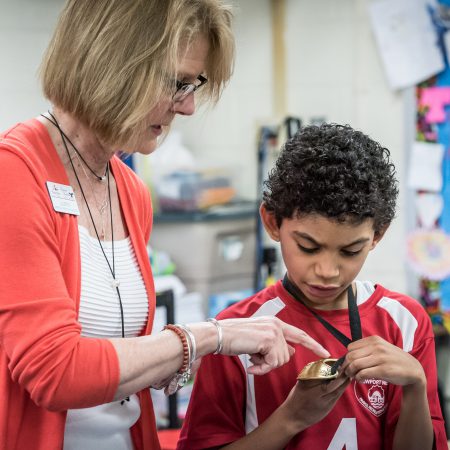 Teacher pointing to an artifact a student is holding